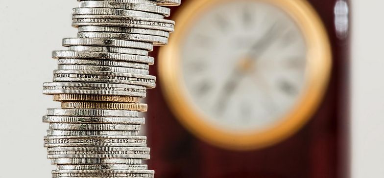 Obrazek przedstawia srebrne monety i zegar